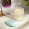 Product photo of a pebble massager lying on a circular stone slab next to a candle in a glass. On the glass, text reads: "my viv"